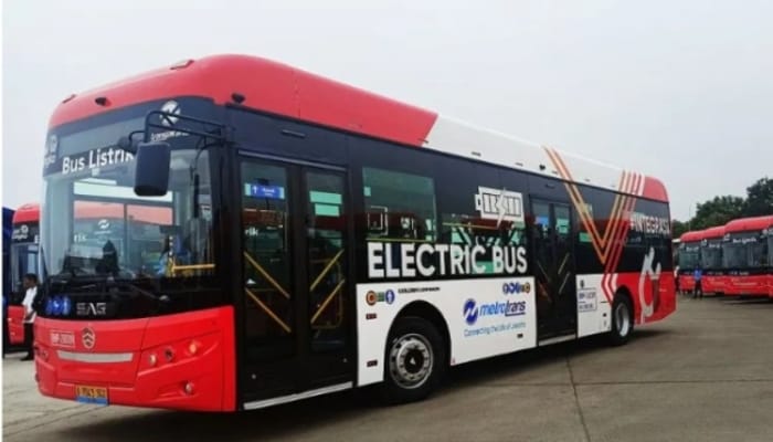 Bus listrik Transjakarta berwarna merah-hitam dengan tulisan "Electric Bus" sedang parkir di area uji coba, siap dioperasikan untuk layanan ramah lingkungan.