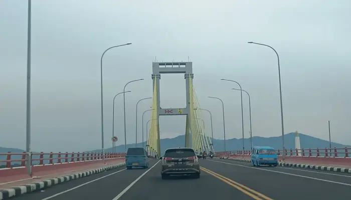 Sulut berpotensi cuaca ekstrem hingga Jumat, Kendaraan melintasi Jembatan Soekarno di Manado di bawah langit mendung.