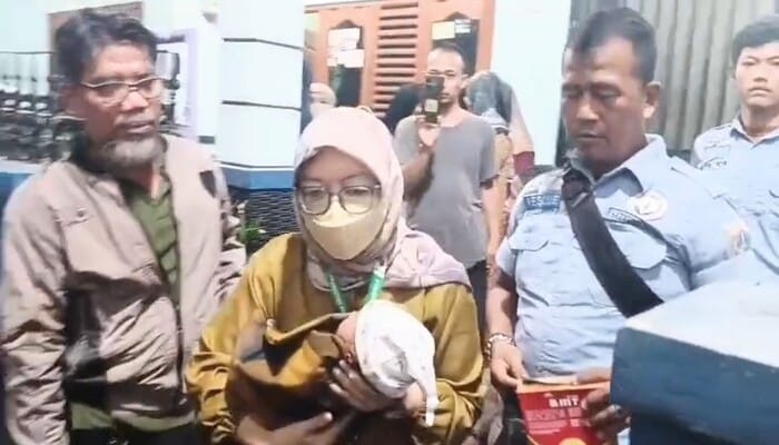 Bayi laki-laki ditemukan di depan rumah, Seorang petugas perempuan membawa bayi yang ditemukan di depan rumah warga Pulogebang, Jakarta Timur, didampingi warga dan petugas lainnya.