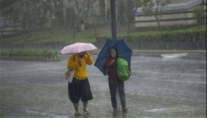 Cuaca Ekstrem! Dua orang berjalan di tengah hujan lebat sambil membawa payung di jalan kota.