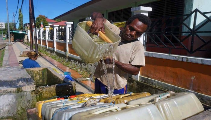 Papua Barat Daya Kekeringan, Seorang pria Papua menuangkan air ke dalam jerigen di tengah krisis air bersih di Papua Barat Daya.